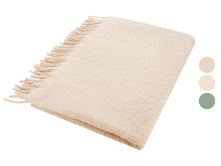 Gevouwen beige deken met franjes, met kleurstalen in beige, crème en groen.