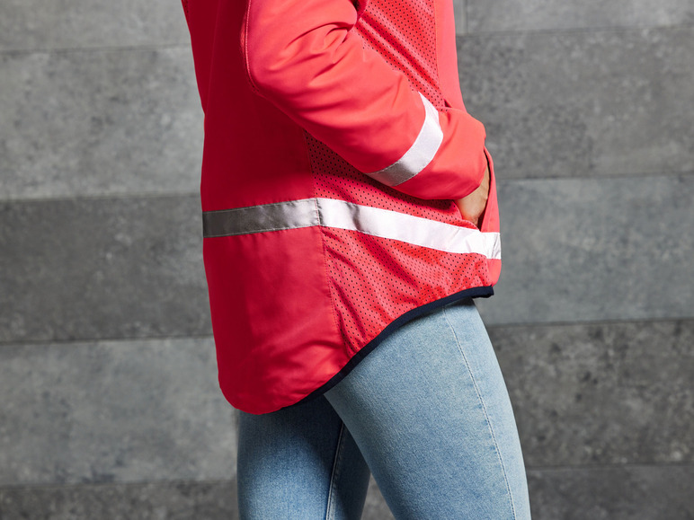 Een roze jack met reflecterende strepen, gedragen over een spijkerbroek.