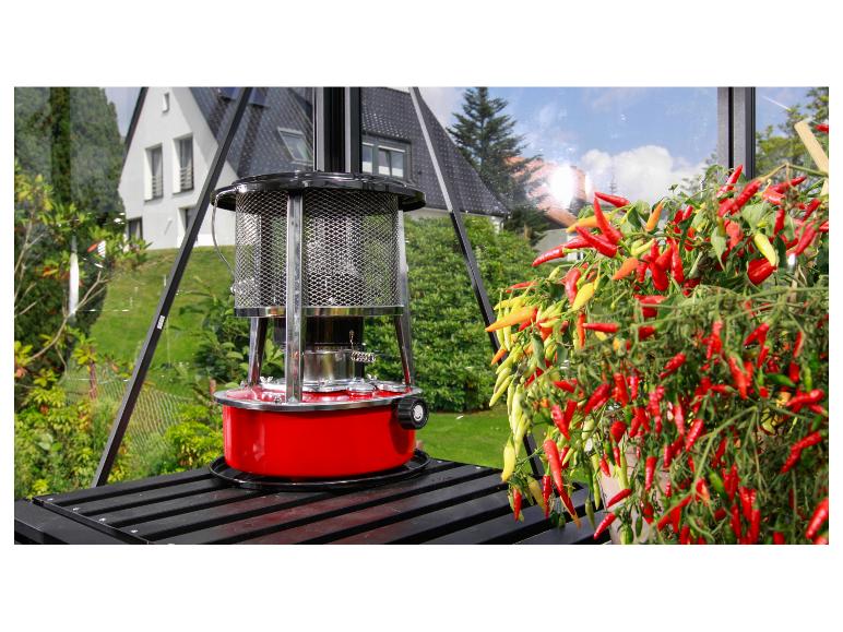 Rode kasverwarming naast een levendige chiliplant in een kas.
