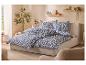 Bed met blauw-wit beddengoed met patroon, houten planken en planten.