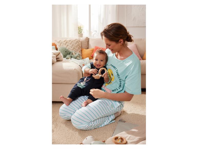 Een moeder in Looney Tunes pyjama speelt met haar baby.