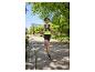Vrouw in sportshirt en hardloopshorts, met hardlooprugzak, rennend in een park.