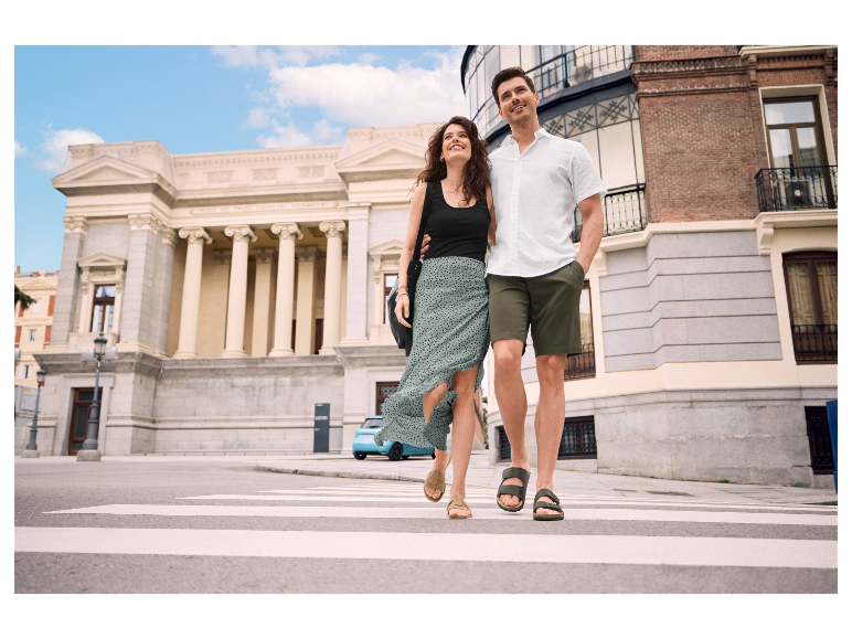 Een stel loopt hand in hand over een zebrapad.