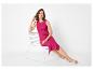 Vrouw in fuchsia mouwloze geribbelde jurk en beige sandalen, zittend op een witte stoel.
