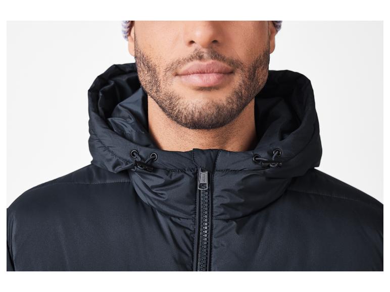 Man met baard draagt een zwarte jas met capuchon en een gebreide muts.