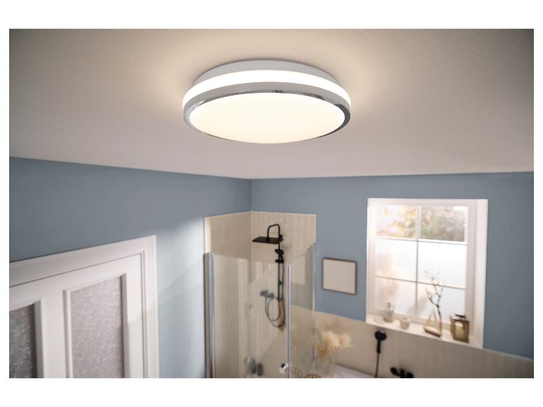 Ronde LED plafondlamp in een badkamer met blauwe muren en douche.