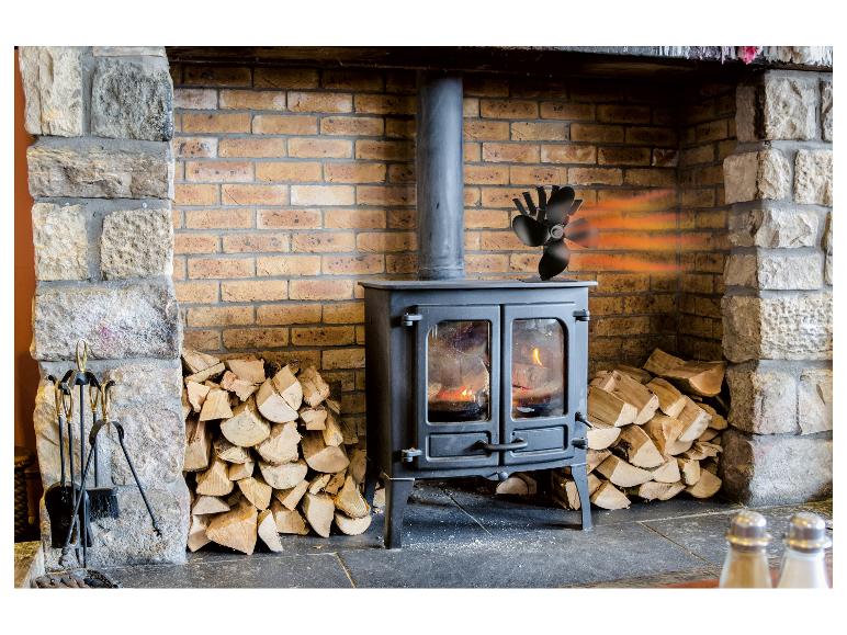 Houtkachel met ventilator, brandhout en haardgereedschap.