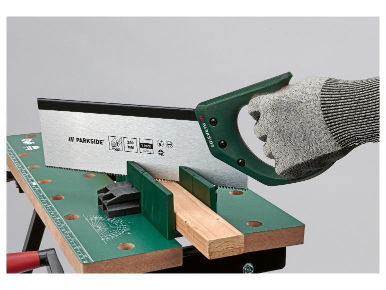 Handzaag zaagt hout op een werkbank, met een veiligheidshandschoen.