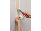 Een persoon plaatst fiberglass tape op een muur met een spatel.