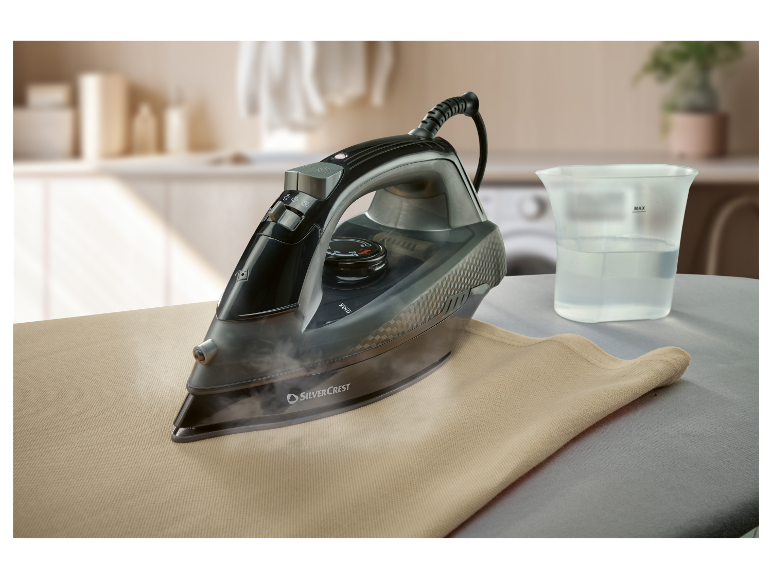 Een SilverCrest stoomstrijkijzer strijkt een beige stuk stof op een strijkplank.