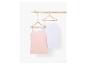 Twee basic tanktops, een witte en een roze, hangen aan houten hangers.