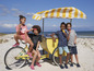 Kinderen op het strand met ijsjes, een fiets en een strandkar.