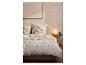 Bed met crèmekleurige bloemen beddengoed en bruine accenten.