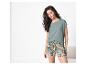 Vrouw in een groen t-shirt en een korte broek met tropische print.