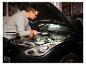 Man met werklamp »The Mechanic« inspecteert automotor.