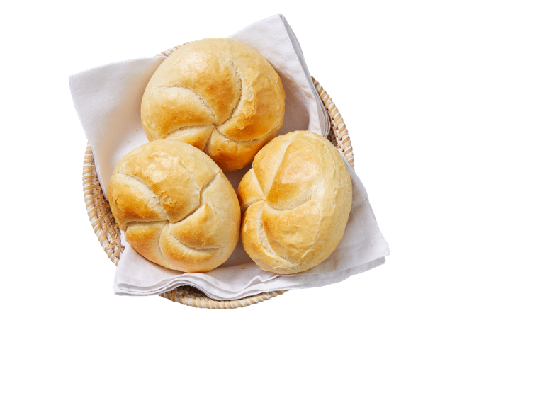 Drie versgebakken broodjes in een rieten mand met een wit servet.