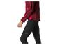 Vrouw in bordeauxrode sportjas en zwarte legging met reflecterende details.