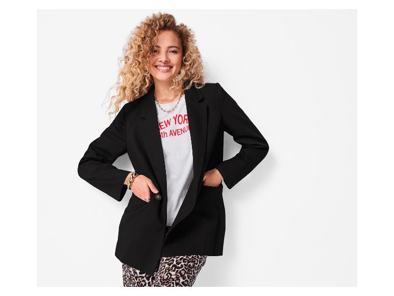 Lachende vrouw in een zwart blazer en luipaardprint broek.