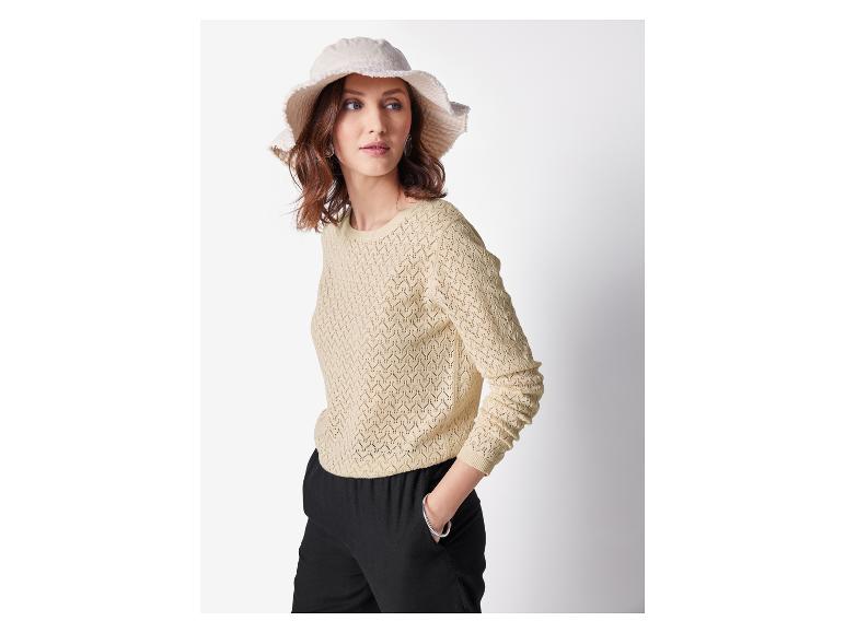 Vrouw in een beige gebreide trui en een lichte hoed.