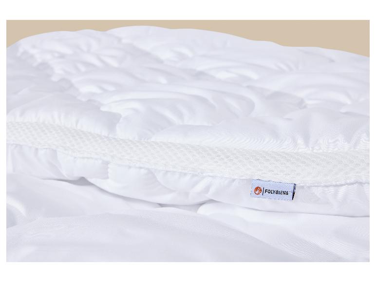Detail van een wit gewatteerd matras met een meshband en een label.