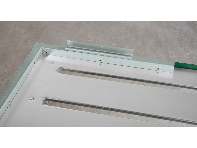 Detail van een metalen constructie met profielen en schroeven, met een groene rand.