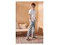 Man in een wit overhemd met korte mouwen, grijze broek en zwarte sandalen in een mediterrane setting.