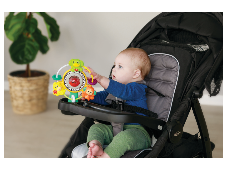 Baby in Graco kinderwagen met speeltje.