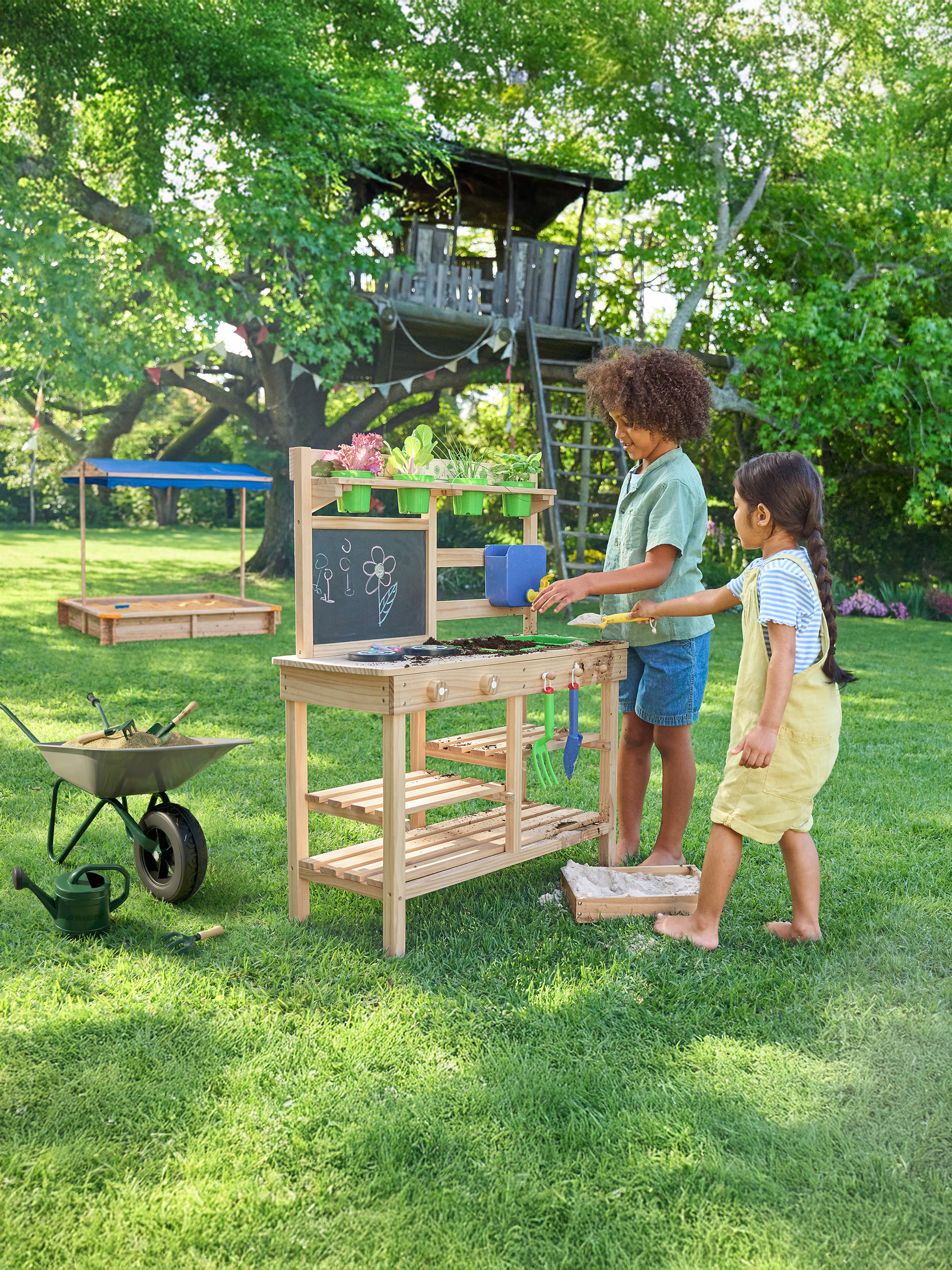 Kinderen spelen met een tuintafel en zandbak in de tuin.