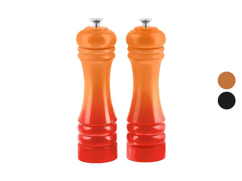 Twee oranje-rode pepermolens met een kleurverloop, staand op een witte achtergrond.