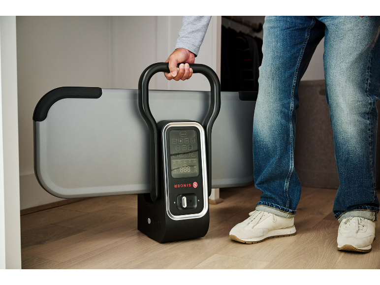 Een man houdt een opvouwbaar fitnessapparaat met digitaal display vast.