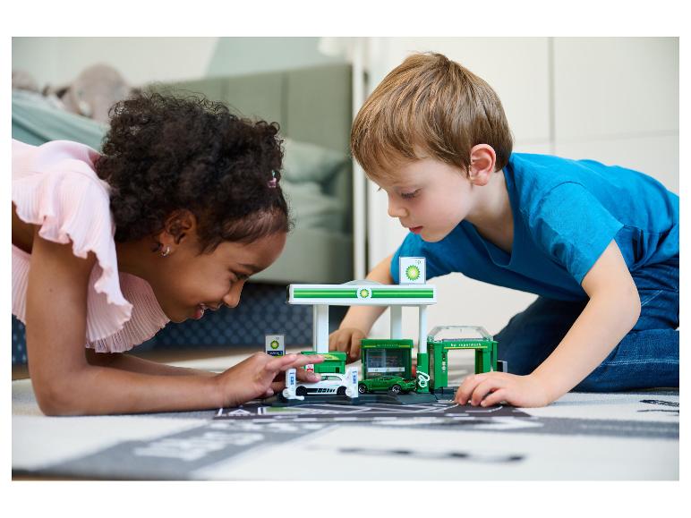 Twee kinderen spelen op de grond met een BP-speelset, inclusief een tankstation.