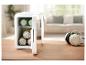 Witte mini-koelkast met drankjes en koptelefoon op een houten tafel in een woonkamer.