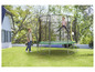 Een meisje springt op een trampoline in de tuin.