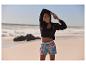 Sportkleding: jas, top en bloemen shorts op het strand.