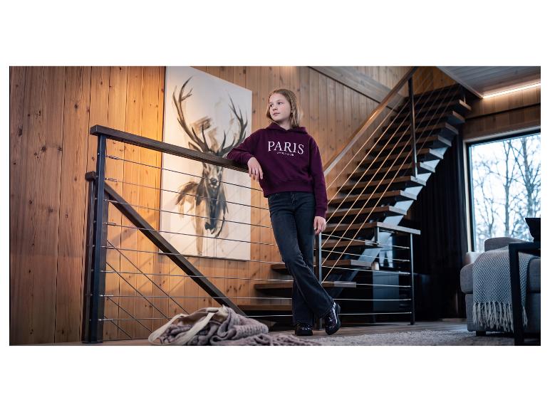 Meisje in een bordeauxrode hoodie met de tekst 'PARIS AMOUR CLUB', zwarte jeans en glimmende schoenen.