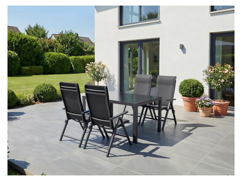 Buiten eethoek met een donkergrijze tafel en vier bijpassende stoelen op een terras.