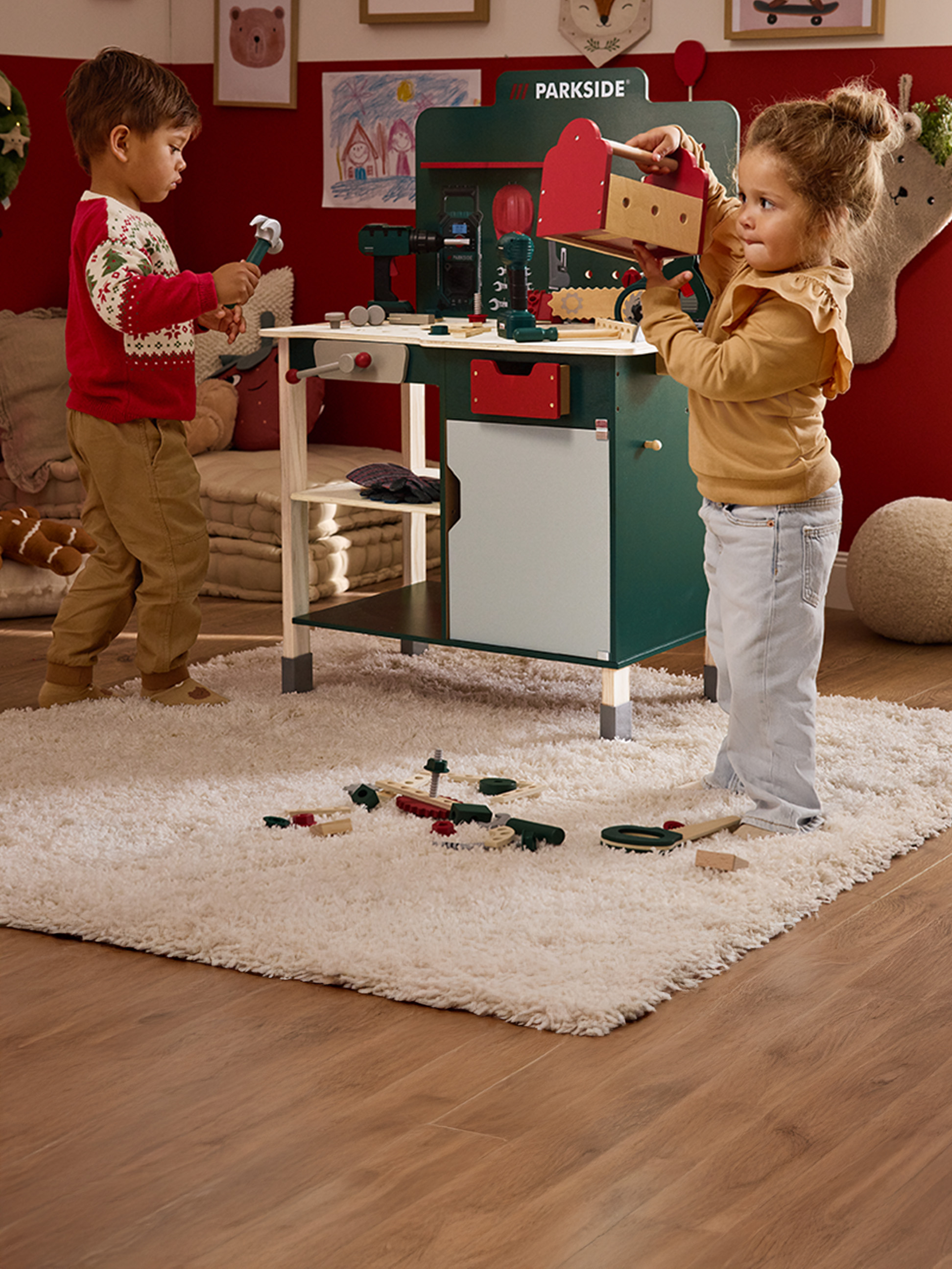 Twee kinderen spelen met een Parkside speelgoedwerkbank en houten gereedschap.