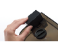 Hand die een zwarte zeepdispenser boven een transparante container houdt.