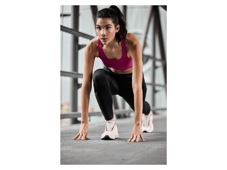 Een vrouw in sportbeha en leggings in een startpositie voor een run.