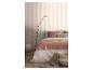 Slaapkamer met gestreept behang, bed met roze en wit beddengoed en een vloerlamp.