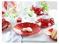 Rood theeservies met stippen, koekjes en witte bloemen op een lichte houten tafel.