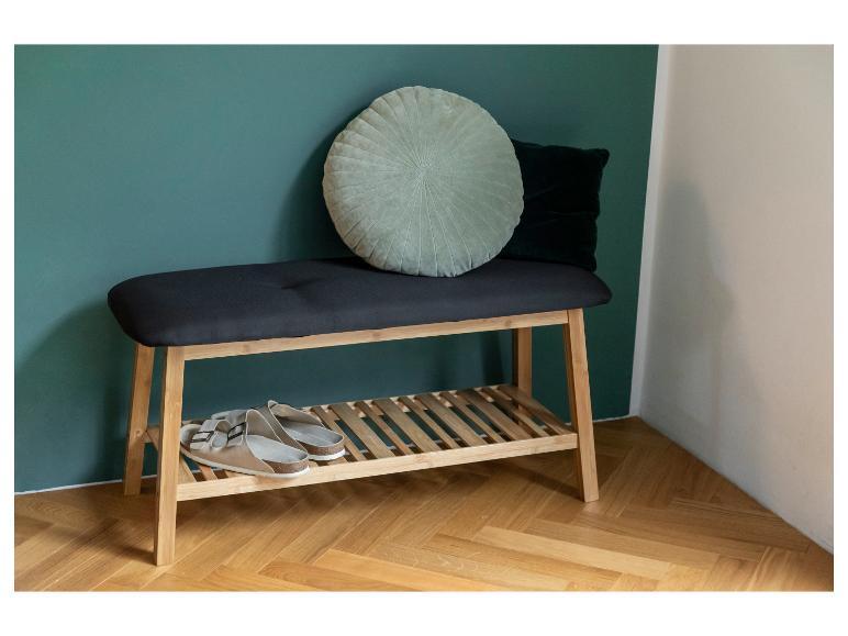 Een bamboe schoenenbank met een gestoffeerde zitting, een paar sandalen en decoratieve kussens.