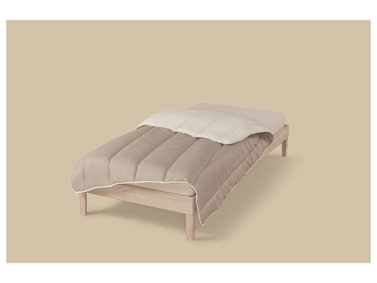 Beige dekbed en laken op een houten bed.