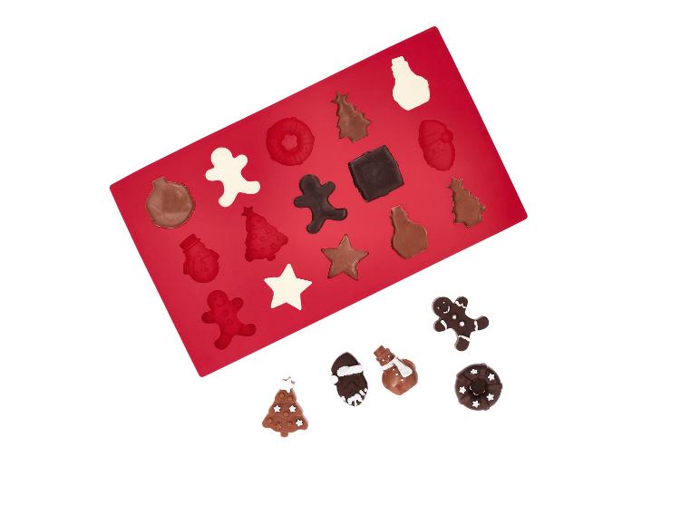 Rode siliconen mal met kerstchocolade en enkele losse chocolaatjes.