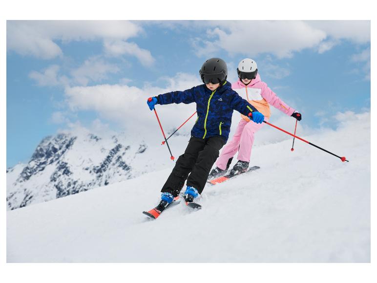 Twee kinderen skiën van een helling in de bergen, gekleed in ski-jassen en -broeken.