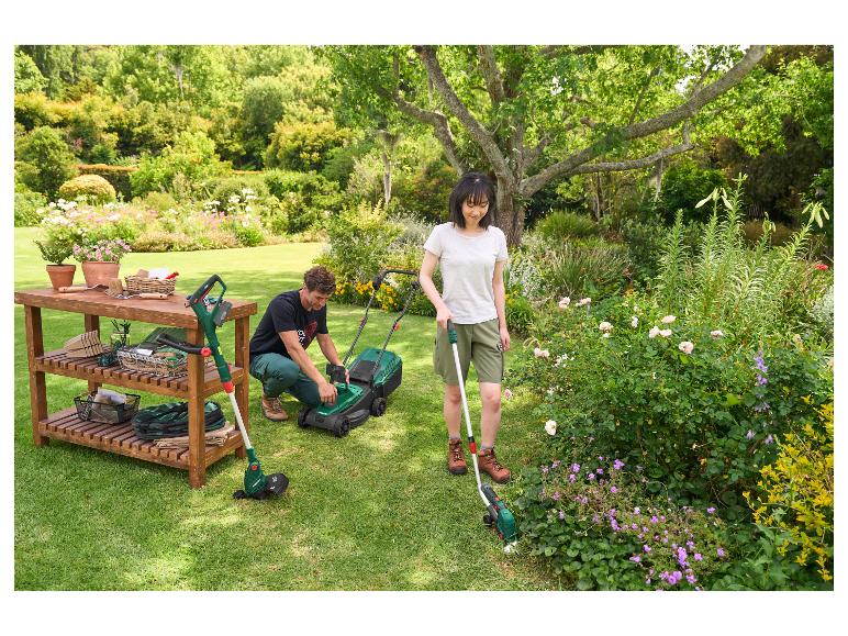 Vrouw gebruikt de PARKSIDE gazontrimmer in een bloeiende tuin naast een man met een grasmaaier.