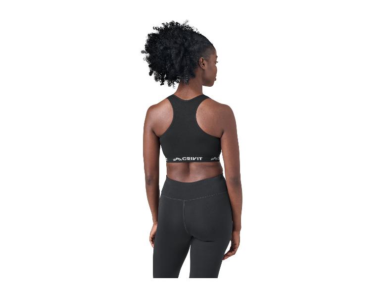 Vrouw van achteren in zwarte sportbeha en legging, opzij kijkend.