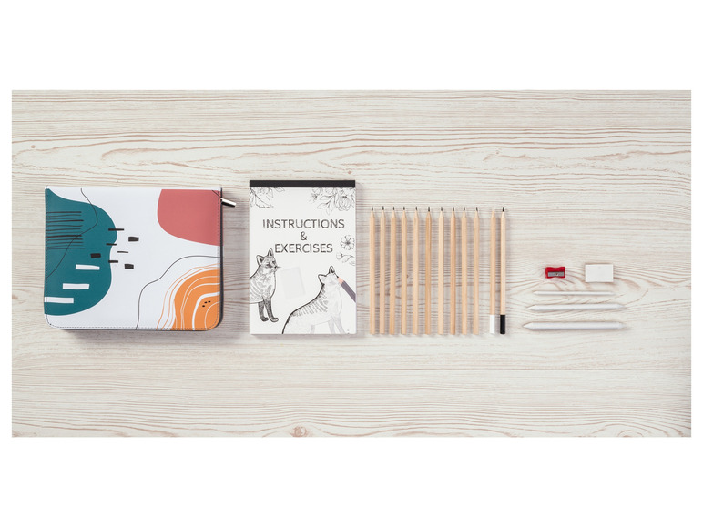 Een notitieboek met geometrische patronen, een oefenboek met vossen en potloden op een houten tafel.