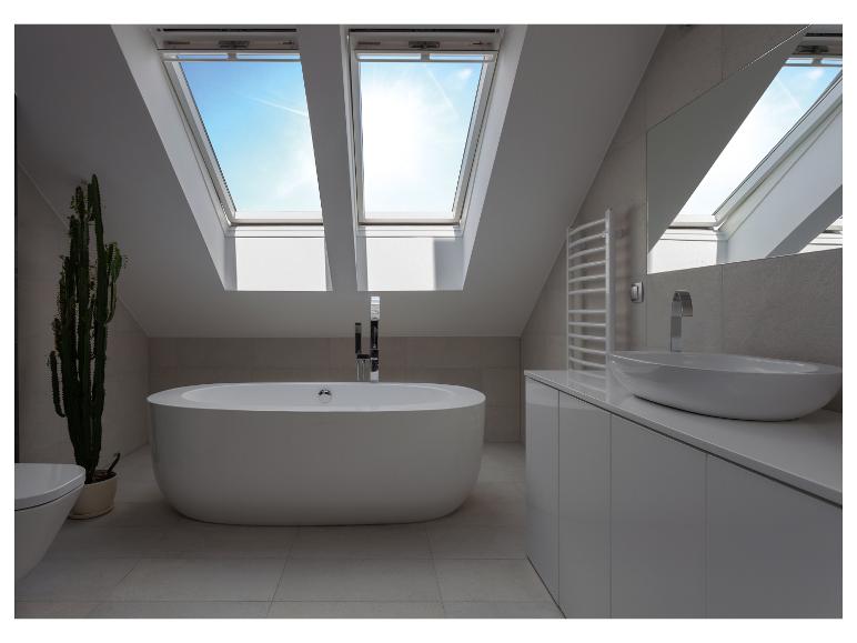 Moderne zolderbadkamer met vrijstaand bad, wastafel en dakramen.