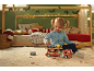 Meisje speelt met houten speelgoedautotransporter in kerstversierde kinderkamer.